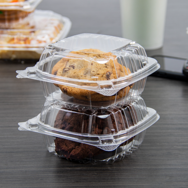 Two stacked clear hinged containers on a table, each holding cookies and brownies for display or takeaway use.