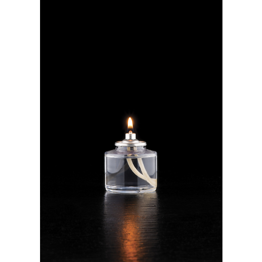 Single Hollowick 26-hour liquid wax disposable candle with a visible flame and clear fuel cell, placed on a dark reflective surface against a black background.