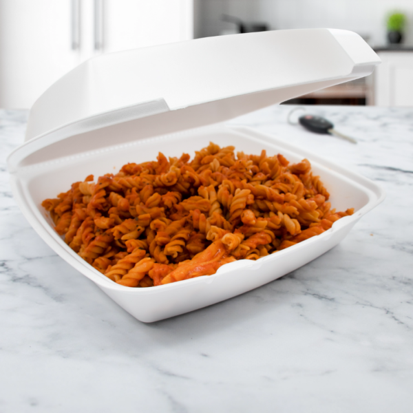 8"x8" White Foam Hinged Carryout Container filled with rotini pasta in red sauce, placed on a marble countertop with the lid partially open.