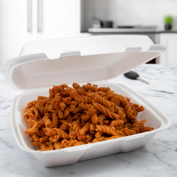 White foam 1-compartment container filled with rotini pasta in a red sauce, placed on a kitchen countertop with a key fob nearby.