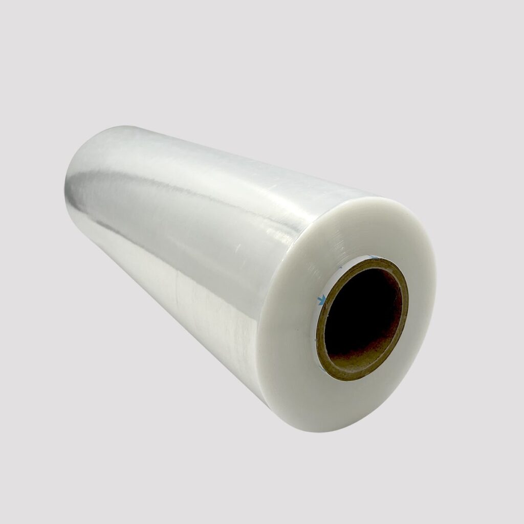 Roll of clear hand stretch wrap film with cardboard core, shown against a light gray background. Used for securing pallets and packaging in shipping or warehouse settings.