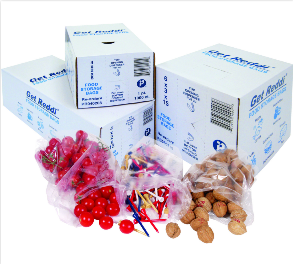 Several white boxes of Get Reddi® Food Storage Bags with blue text and branding, labeled with different sizes and quantities. In front of the boxes, clear plastic bags are filled with red cherries, cocktail picks, and walnuts, showcasing the bags' transparency and storage versatility.